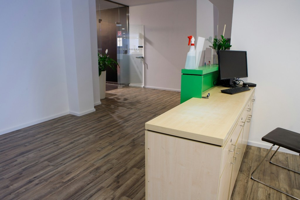 An empty office reception desk with a monitor and keyboard, nobody behind it